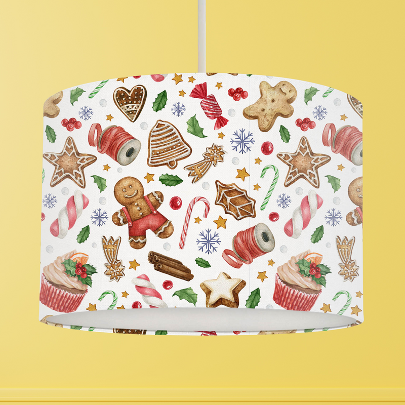 This Christmas themed lampshade features a fun festive pattern of sweets, berries, holly leaves, cupcakes, gingerbread cookies and candy canes on a white background. 