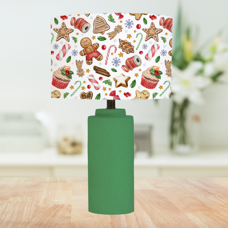 This Christmas themed lampshade features a fun festive pattern of sweets, berries, holly leaves, cupcakes, gingerbread cookies and candy canes on a white background. 