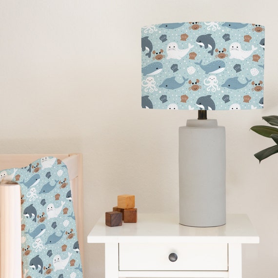 Children's bedroom and nursery lampshade lightshade for ceiling fitting or lamp base featuring sweet little sea creatures including whales, crabs, seals and dolphins on a light blue background.