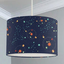 Children's bedroom and nursery ceiling lampshade featuring a space scene of assorted planets in a solar system in oranges, reds, yellows and greens on a dark blue background.